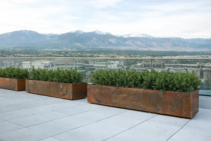 Custom weathered steel planter boxes on a rooftop terrace