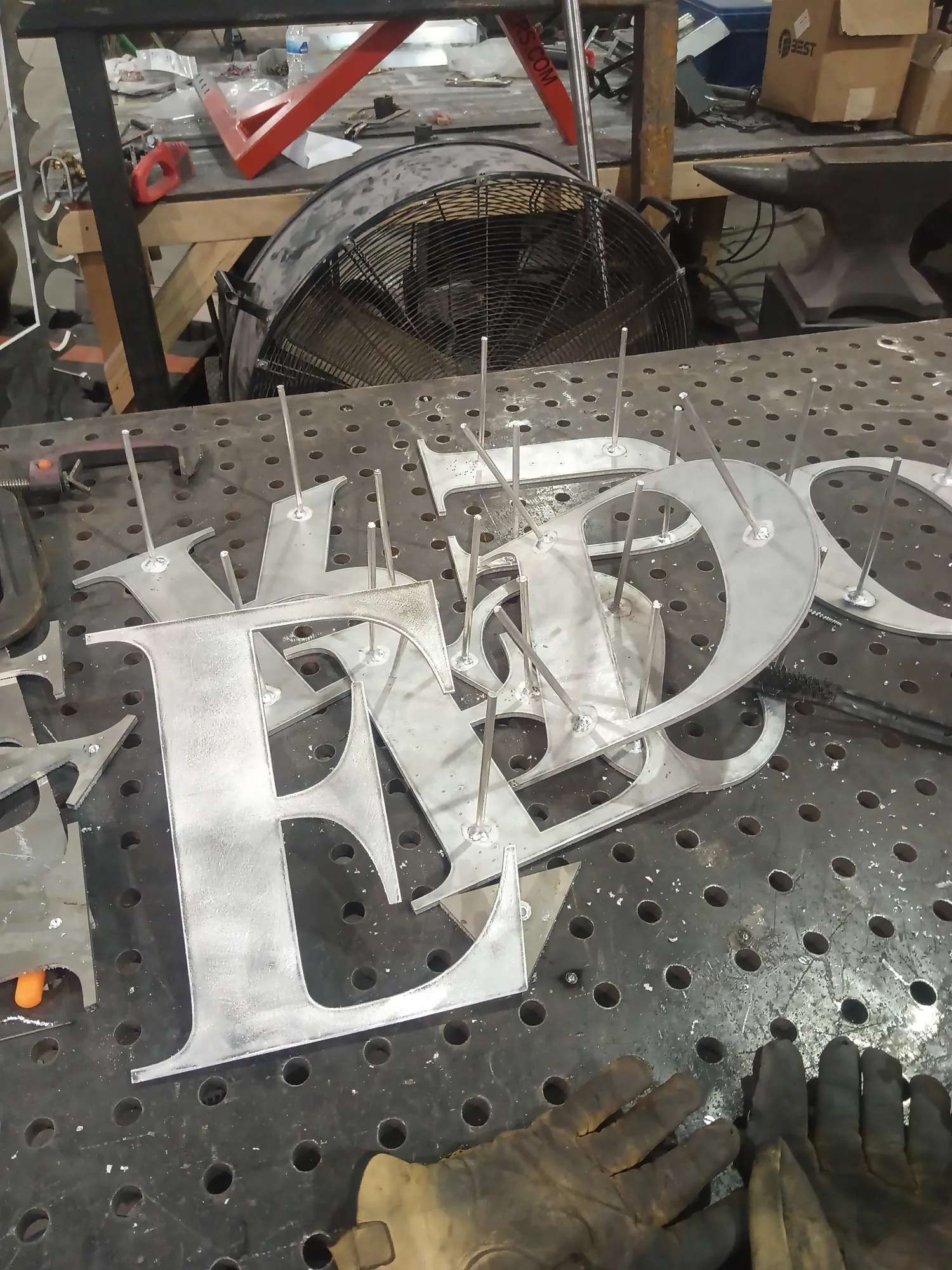Custom-cut steel letters being welded on the fabrication table
